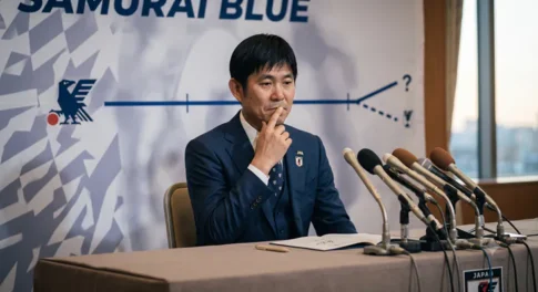 SAMURAI BLUEのバックボードを背に、契約延長について口元に手を当てて熟考する森保一監督のバストアップ写真